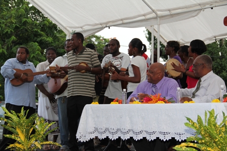 Residents accompanied by the Barnes Ghaut String Band presenting musical gospel renditions while (seated at table L-R) Minister for Social Development on Nevis and Premier and Area Representative Hon. Joseph Parry look on