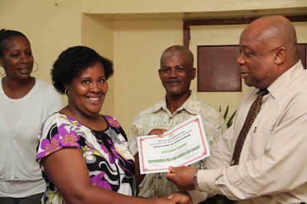 One of three female participates in the Basic Plumbing Installation six week course offered by the Ministry of Social Development Ms. Sylvia Dore of Brown Hill Village receives her Certificate of Achievement from Social Development Minister Hon. Hensley Daniel while (L-R) Events Coordinator in the Ministry of Social Development Ms. Tonya Powell and Course Tutor Mr. Alex Claxton look on