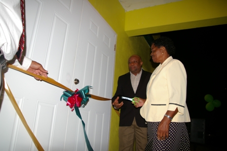  Minister for Social Development on Nevis Hon. Hensley Daniel looks on as Villager Ms. Soreatha Franc cuts the ribbon to the new Fountain Community Centre