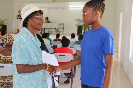 Nevisian lass Ms. Ercha Stapleton (r) interacts with her senior Mrs. Oretha “Lizzie” Wilkerson a member of the St. Johns Mothers Union at International Women’s Day celebrations at the Cotton Ground Community Centre on Nevis