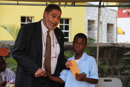 Deputy Governor General His Honour Eustace John presents Alexander Hamilton Scholarship package to Mr. Jah-larney Brookes of the Charlestown Secondary School