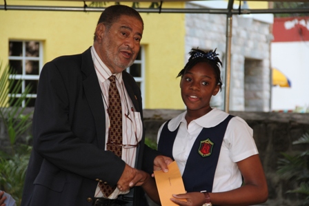 Deputy Governor General His Honour Eustace John presents Alexander Hamilton Scholarship package to Ms. Kyla Seabrookes of the Charlestown Secondary School