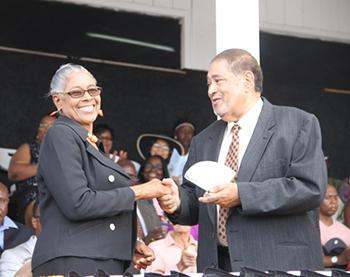 Gloria Anslyn receives an award on behalf of her mother Wilma Cornelius from His Honour Eustace John Deputy Governor General s for her services in Industry and Commerce