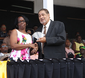 Leonie Dasent receives an award from His Honour Eustace John Deputy Governor General for her services in Education