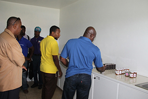 Minister of Agriculture on Nevis Hon Alexis Jeffers looks at products made at the Nevis Agro Processing Centre at Prospect on November 04, 2014, with Centre Manager Dwight Brown (left), Permanent Secretary in the Ministry of Agriculture Eric Evelyn (standing behind) and other officers of the Department of Agriculture looking on