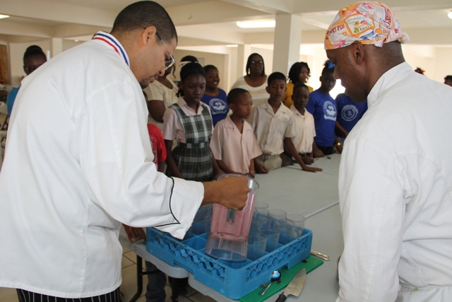 (L-R) Food and Nutrition Specialist attached to the School Meals Programme on Nevis, Executive Chef Michael Henville and Celebrity Chef of Atlanta Marvin Woods,   demonstrates to students of the Charlestown Primary School how to make healthy snacks at a Mini Chef Academy session at the school’s kitchen on February 24, 2015