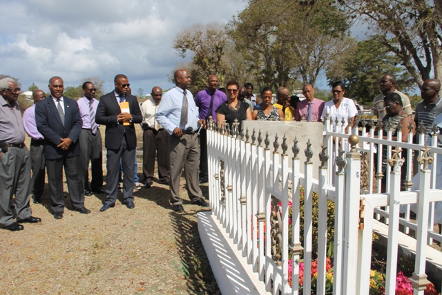 At the graveside of the late Malcolm Guishard at Bath Cemetery to honour his memory on June 11, 2015 are (front row l-r) Theodore Hobson, Premier of Nevis Hon. Vance Amory, Deputy Premier Hon. Mark Brantley, Cabinet Secretary Stedmon Tross, Widow of the late Malcolm Guishard Yvonne Guishard and their daughter Shanelle and Legal Advisor in the Nevis Island Administration Colin Tyrell