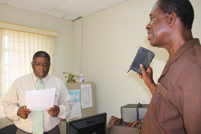Nelson Stapleton (r) being sworn in as a Registration Officer for Constituencies 10 and 11 by Supervisor of Elections Elvin Bailey at the Electoral Office on Nevis on July 20, 2015