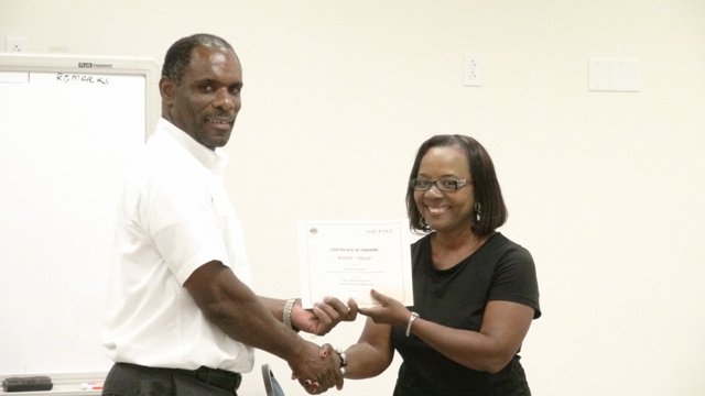 Permanent Secretary in the Ministry of Finance Colin Dore presents one of 13 participants in the Small Enterprise Development Unit’s Quick Books Accounting workshop with a certificate of completion at the Nevis Disaster Management Department‘s conference room at Long Point on October 23, 2015