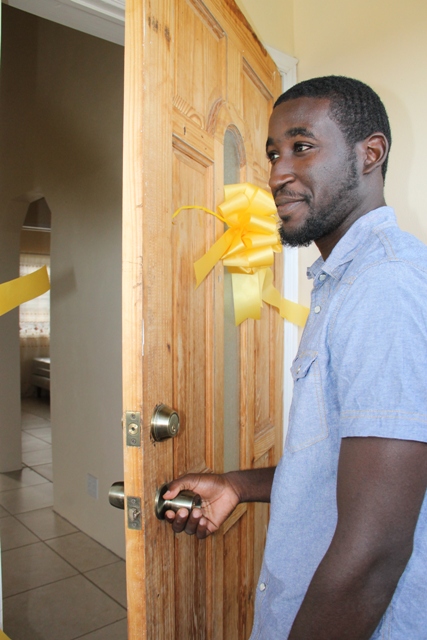 Nevis’ most accomplished junior athlete Adrian Williams opens the door to his new home, a two bedroom furnished house at Eden Brown Estate after he was given the keys by Nevis Island Administration in collaboration with the Nevis Housing and Land Development Corporation at the official Handing Over Ceremony at Eden Brown Estate on December 16, 2015