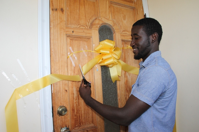 Adrian Williams cuts the ribbon to officially open his two-bedroom house moments after he was given the keys by Nevis Island Administration in collaboration with the Nevis Housing and Land Development Corporation at the official Handing Over Ceremony at Eden Brown Estate on December 16, 2015