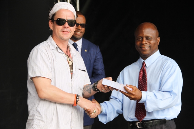 Permanent Secretary in the Premier’s Ministry responsible for Education Wakely Daniel receives tickets, to attend the opening night of Nevis Blues Festival, for teachers from renowned Blues singer Ian Seigal on behalf of organisers of the festival during a presentation ceremony at Oualie Bay on April 12, 2016  