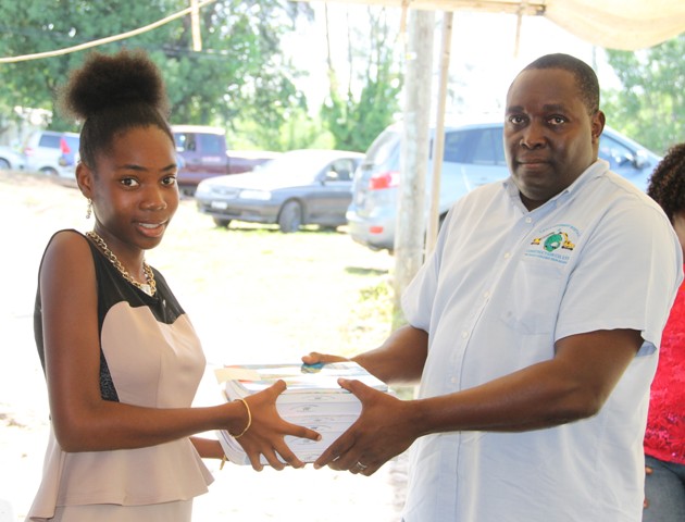 Robelto Liburd, Managing Director at LEFCO Equipment Rental and Construction Company Ltd. makes a special presentation to Adeilyah Moore of Ramsbury on August 15, 2016, as part of the Cane Garden Community Improvement Club Incorporated Text Book Initiative Drive