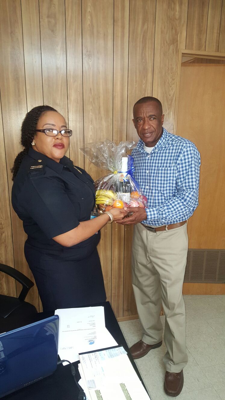 Wendy Wilkes, Senior Customs Officer at the Customs and Excise Department on Nevis presents a fruit basket to Vernon Evelyn, a past customs officer as a token of appreciation from the Department on International Customs Day on January 26, 2017