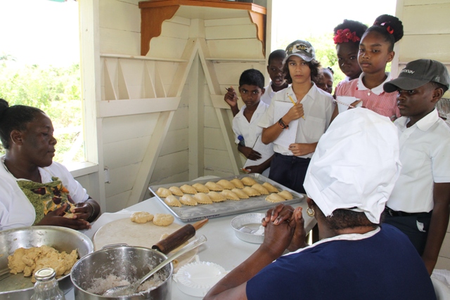 Patricia Thompson, Manager of the Nevisian Heritage Village accompanied by Lydia Lawrence of the Ministry of Tourism, tells students of the Montessori Academy Nevis about making tarts the Nevis way at the Nevisian Heritage Village during the Ministry of Tourism’s Open Day, a part of Exposition Nevis on May 11, 2017