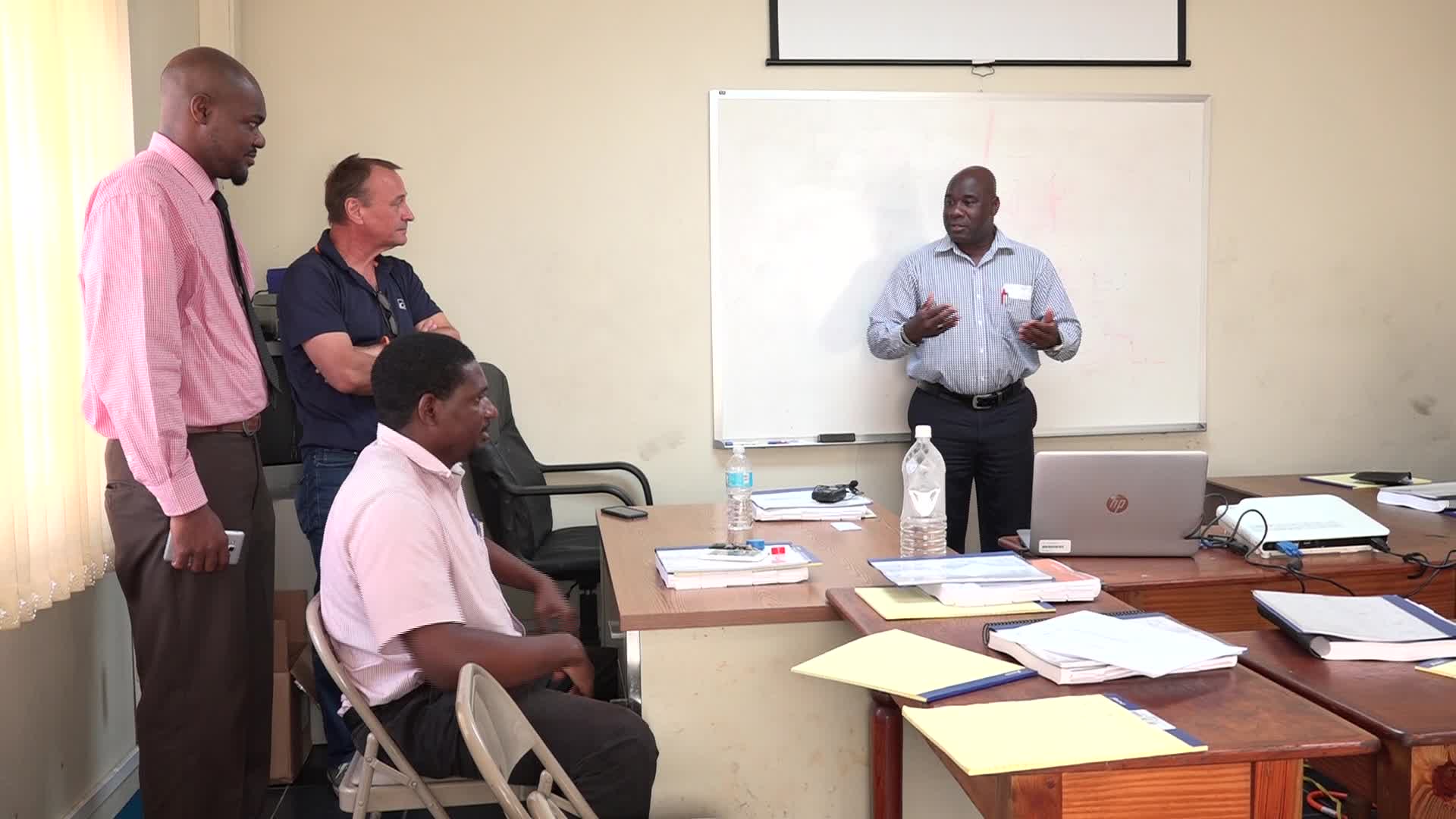 (l-r standing) Mr. Michael Webbe, Nevis Electricity Company Limited’s Senior Human Resource Officer, Mr. Matti Kakko, Senior Instructor Technical Service Turbochargers Wӓrtsilӓ North America Inc. and a participant at the Nevis Electricity Company Limited training session July 31, 2017 at the Prospect Power Plant meeting room listening to Hon. Alexis Jeffers, Minister of Public Utilities on Nevis