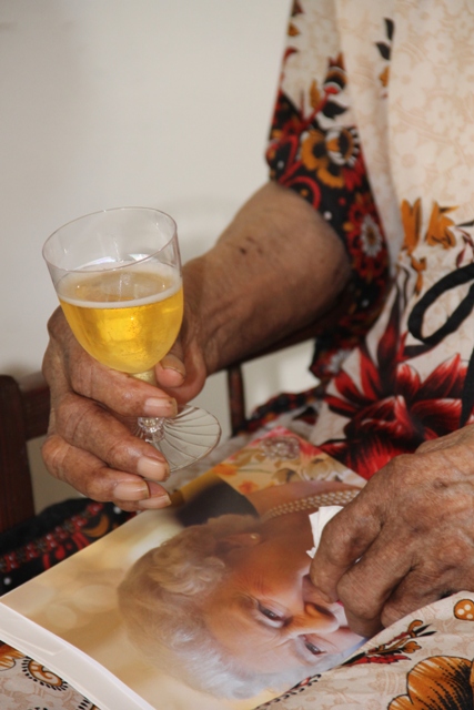 Centenarian Eileen Swanston Smithen holds her royal birthday card from Her Majesty Queen Elizabeth II in one hand and a glass of chilled cider in the other, after receiving the card from Governor General of St. Kitts and Nevis His Excellency Sir Tapley Seaton at her home in Zion Village on July 13, 2017, to mark her 100th birthday 