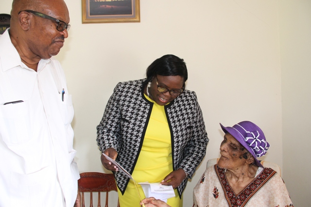 (L-r) Governor General of St. Kitts and Nevis His Excellency Sir Tapley Seaton and Hon. Hazel Brandy Williams, Junior Minister in the Ministry of Social Development in the Nevis Island Administration share a light moment with Centenarian Eileen Swanston Smithen, moments after he presents her with the royal birthday card from Her Majesty Queen Elizabeth II at her home in Zion Village on July 13, 2017