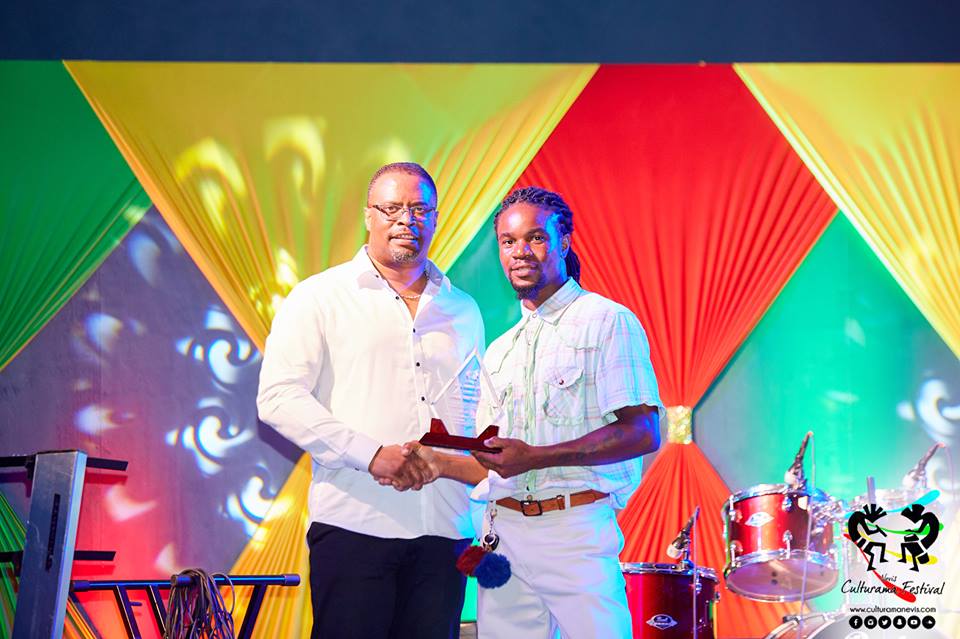 Hon. Mark Brantley, Deputy Premier of Nevis and Minister of Culture presents token of appreciation to Glenville “DJ Denny” Fahie on behalf of Samuel “Fish” Richards on July 04, 2017, for his long standing contributions at the Cultural Village