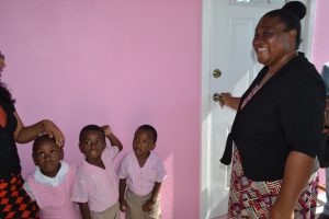 Elated Gingerland Preschool Supervisor Mrs. Pamella Elliott-Lawrence, opens the door to the newly renovated and expanded Gingerland Preschool with some students and staff looking on, moments after receiving the keys from education officials on December 12, 2017