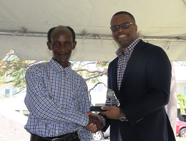 Minister of Health Hon. Mark Brantley presents a plaque to retired Orderly Mr. Anthon “the dancing orderly” Hicks on behalf of the Alexandra Hospital, at the hospital’s Pre-Christmas Programme on December 13, 2017, for his dedication to duty