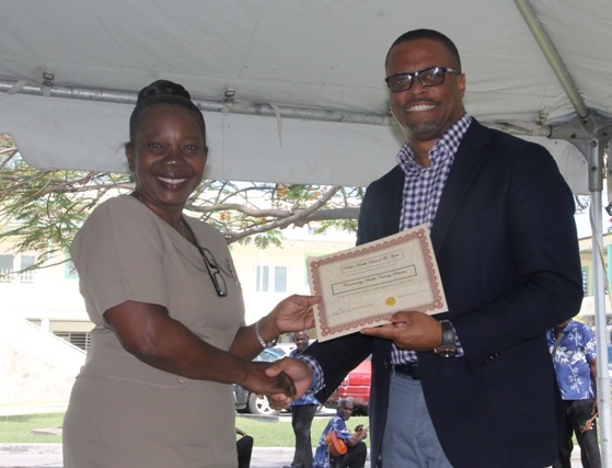 Minister of Health Hon. Mark Brantley presents a plaque to Ms. Lolita Williams on behalf of the Alexandra Hospital at the hospital’s Pre-Christmas Programme on December 13, 2017, for her contribution to the Housekeeping Department