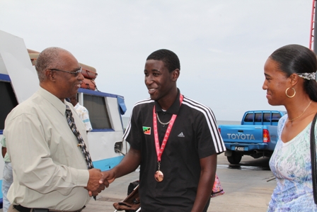 Premier of Nevis welcomes Nevis’ Bronze winning medallist at the Commonwealth Youth Games in the Island of Man Mr. Adrian Williams home while his mother Ms. Glenett Williams looks on