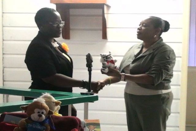 Project Officer for School Libraries Mrs. Marva Roberts accepts teddy bears from Mrs. Sonita Daniel on behalf of the Nevis Association of South Florida.