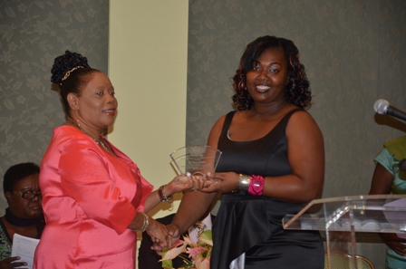 Ms. Petrona Freeman of the Charlestown Primary School receives plaque from Mrs. Sonita Daniel wife of Deputy Premier Hon. Hensley Daniel