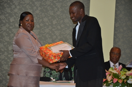 Mr. Kirmani Webbe of the Charlestown Secondary School, the only male teacher awarded in the Teacher of Excellence category receives one of his gifts from Principal Education Officer Mrs. Lornette Queeley-Connor. Looking on is Premier of Nevis Hon. Joseph Parry