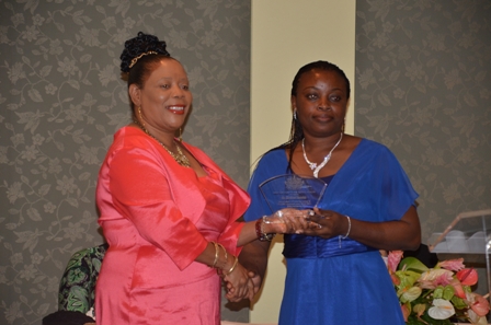 Ms. Adebimpe Akomolafe of the Lyn Jeffers Primary School receives plaque from Mrs. Sonita Daniel wife of Deputy Premier Hon. Hensley Daniel
