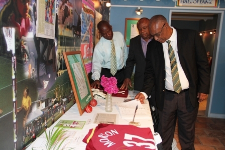 (L-R) Cabinet Secretary in the Nevis Island Administration Mr. Ashley Farrell, Deputy Premier and Minister of Youth and Sports on Nevis Hon. Hensley Daniel and Premier of Nevis Hon. Joseph Parry view the special tribute to Runako Morton at the Sports museum in Charlestown one day ahead of his funeral service on March 17, 2012. Mr. Farrell’s tribute read: “Ashley S. Farrell. Gone too soon, may your legacy live on!”