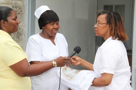 Nevisian Mrs. Marilyn Walters-Drew (r) hands over gift to Nurse Adrienne Ward for patients of the Alexandra Hospital and residents of the Flamboyant Nursing Home on Nevis. Hospital Administrator Ms. Grace Elliott (extreme left) looks on