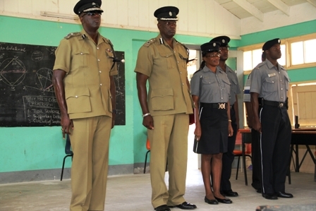 Commissioner of Police in the Royal St. Christopher and Nevis Police Force Celvin G. Walwyn, Assistant Commissioner of Police responsible for the St. Christopher and Nevis Royal Police Force Nevis Division Robert Liburd, Sergeant in charge of the Gingerland Police Station Paulette Bartlette and other officers stationed at the Gingerland Police Station standing at attention during a rendition of the national anthem at the Gingerland Secondary School