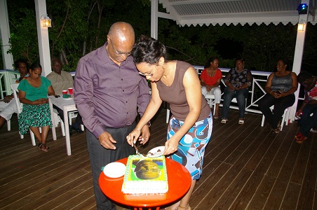 Premier of Nevis, Hon. Joseph Parry cutting his cake with the assistance of his daughter Sonya Parry