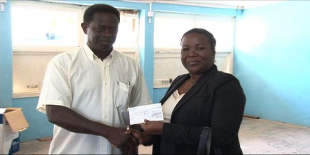 Chairman of UK-based St. Kitts/Nevis & Friends Association, Randolph Charles, hands over a cheque of £600 to Permanent Secretary in the Ministry of Education, Lornette Queeley-Connor at the Charlestown Secondary School on March 26, 2014