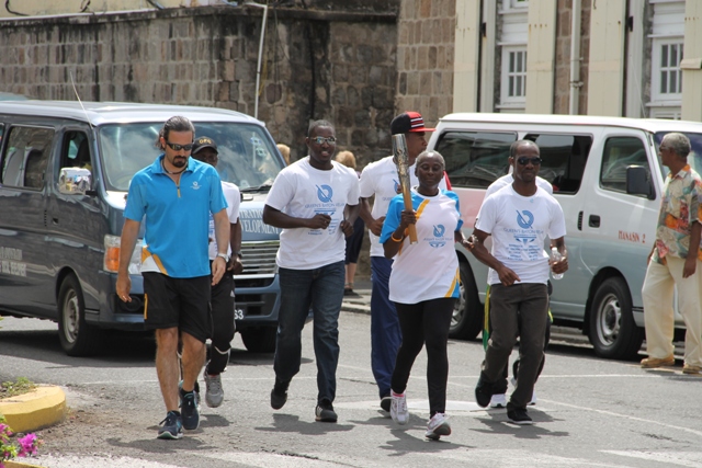 Athetes help to carry the Queen’s Baton around the island of Nevis on March 29, 2014