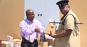(L-R) Permanent Secretary in the Premier’s Ministry Wakely Daniel hands over donation from the Dennis and Linda Thomas in Florida for the inmates of the Prison Farm to Principal Officer in Charge of the Prison Farm on Nevis Lawson Crosse on August 07, 2014