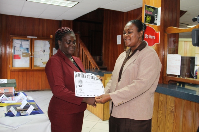 Customer Service Manager at the Nevis Post Office Carol Jeffers (r) presents “Officer of the Year” award for 2014 to Marva Morton-Parris at the Charlestown Post Office