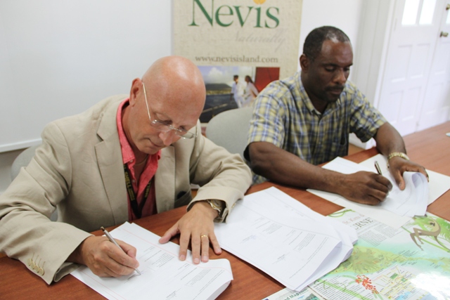(L-R) Director of Caribbean Helicopters Ltd. (CPL) Neil Dickinson and Permanent Secretary in the Ministry of Finance in the Nevis Island Administration (NIA) Colin Dore sign the agreement between CHL and the NIA for the provision of airlift between Nevis and Antigua, at the Nevis Tourism Authority’s Visitor Centre on February 13, 2015