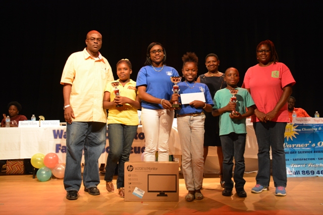 (l-r) 3rd place winner Elizabeth Pemberton Primary’s Denzil and D’Rhys Stanley, Family Book Feud 2015 winners Charlestown Secondary’s Shenel Nisbett and Shevonel Williams, Principal Education Officer in the Department of Education Palsy Wilkin and 2nd place winner Montessori Academy’s Casandra and Lincoln Sandiford, at the end of the 6th annual joint School Libraries and Department of Education’s Warner’s One Stop Family Book Feud on July 11, 2015, at the Nevis Performing Arts Center
