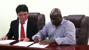 Minister responsible of Fisheries Hon. Alexis Jeffers signs an agreement to amend the grant agreement for the project for development of a Community Fisheries Centre in Charlestown at his Charlestown Office while General Manager of the JICA office in the Dominican Republic Morita Tatsuya looks on.