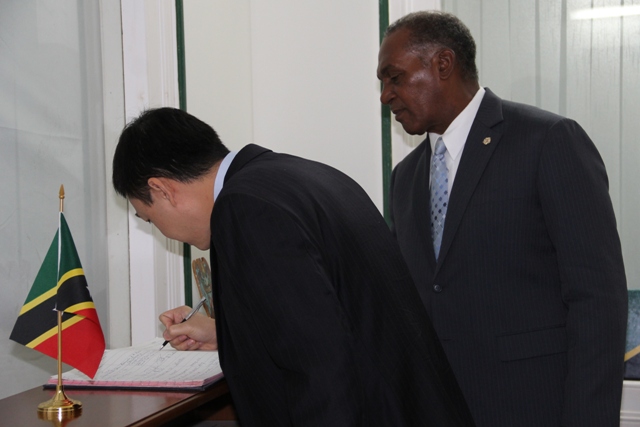 Minister Counsellor in the Vietnam Embassy Mr. Duong Hai Hung signs the visitor’s register at the Premier’s office on November 24, 2015, while Premier of Nevis Hon. Vance Amory looks on