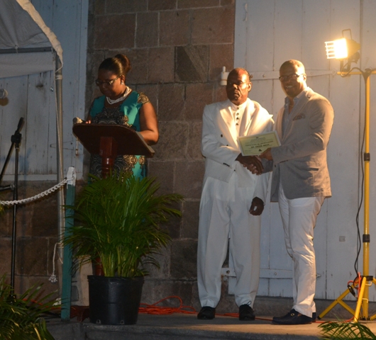 Minister of Social Development on Nevis Hon. Mark Brantley presents honouree Frank Mills of the St. James Parish with a certificate of appreciation, at the annual Charlestown Christmas Tree lighting Ceremony on December 02, 2015, for his outstanding contribution to the community