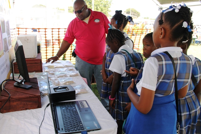 Rohan Claxton, Livestock Extension Officer in the Department of Agriculture explains dry season livestock production to students of the St. James' Primary School at the Ministry of Agriculture Open Day at the Villa Grounds in Charlestown on March 17, 2016