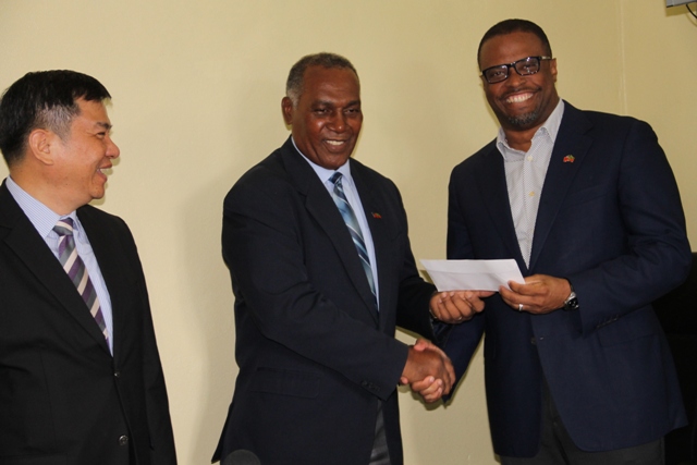 Premier of Nevis Hon. Vance Amory (l) hands over cheque from the Republic of China (Taiwan), for assistance to the Nevis Cultural Development Foundation, to Deputy Premier and Minister of Culture Hon. Mark Brantley on April 19, 2016, at Bath Hotel. Republic of China (Taiwan) Ambassador to St. Kitts and Nevis His Excellency George Gow Wei Chiou looks on