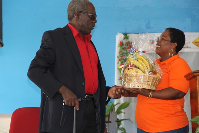 Ezzard Charles, Patron of Charlestown Secondary School Multi-Purpose Centre’s Technology and Art Exhibition receives a fruit basket and plaque from teacher Ms. Mavis Parris on behalf of the Centre, at the opening ceremony on May 26, 2016