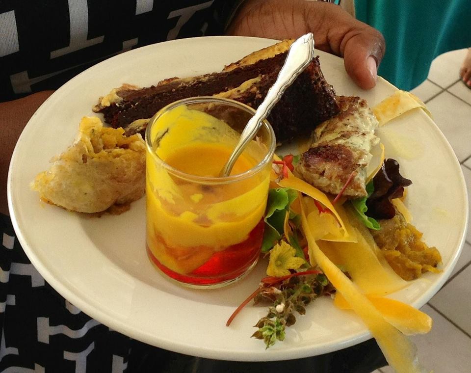 Samples from a variety of pumpkin-infused dishes - chocolate cake topped with pumpkin custard, roti with chicken and pumpkin, pumpkin cream and Jello, green foraged salad with pumpkin - featured on one plate from a restaurant on Nevis, at 2016 Restaurant Week tasting showcase at Mount Nevis Hotel on July 16, 2016