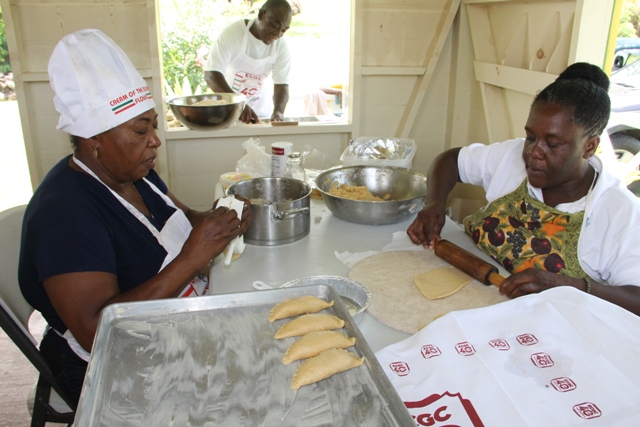 Patricia Thompson, Manager of the Nevisian Heritage Village (l) and Lydia Lawrence making coconut tarts while Mr. Winston Fyfield prepares rolls for baking at the Ministry of Tourism’s Exposition Nevis Open Day at the Heritage Village at Fothergills on May 11, 2017