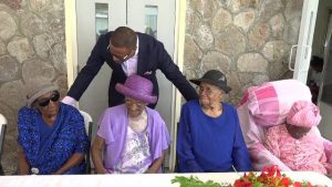 Hon. Mark Brantley, Deputy Premier of Nevis and Senior Minister in the Ministry of Social Development, sharing a light moment with four of the eight centenarians on Nevis at a ceremony at the Flamboyant Nursing Home to honour them. It was hosted by the Social Services Department, Seniors Division in the Ministry of Social Development